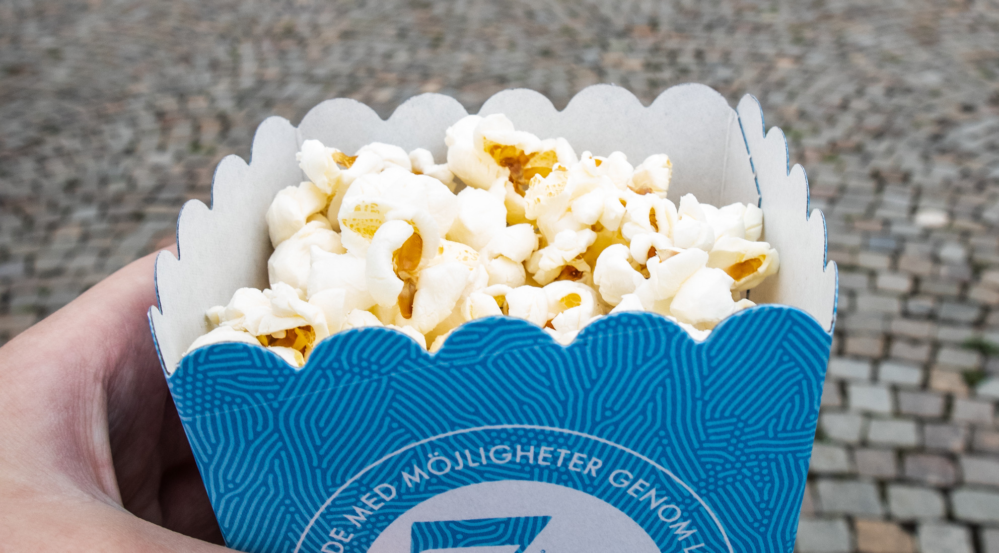 popcorn hand som håller en blå bagare med popcorn